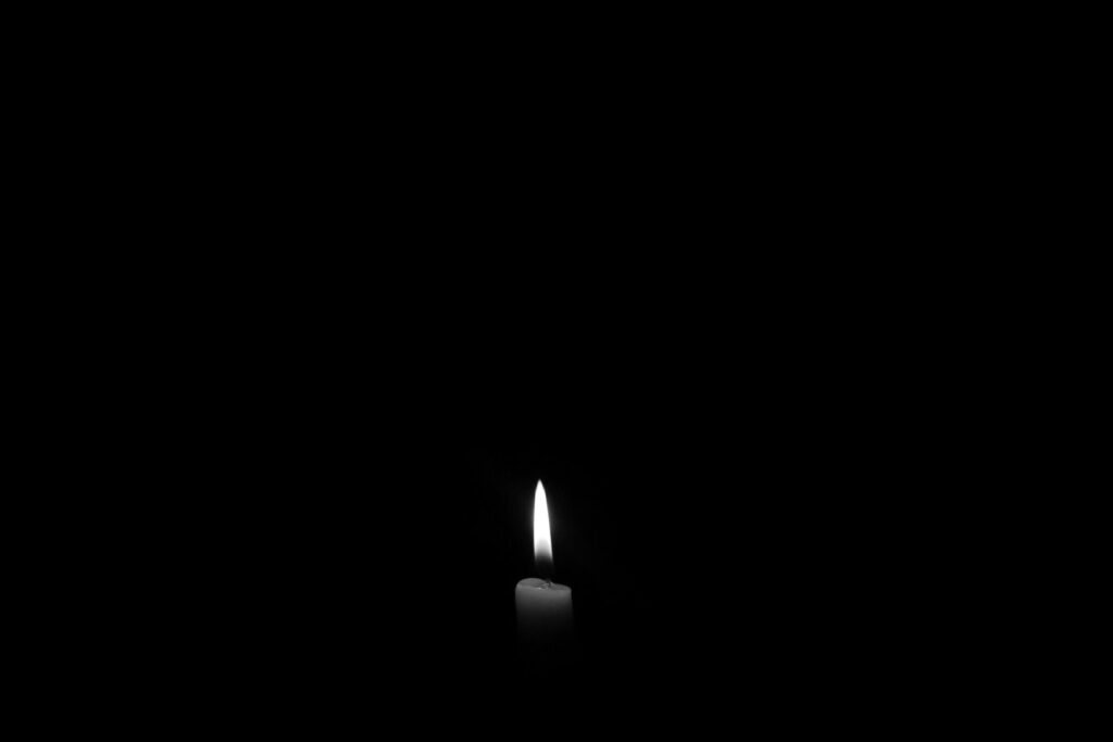 A solitary candle flame against a plain black backdrop, epitomizing simplicity and tranquility.